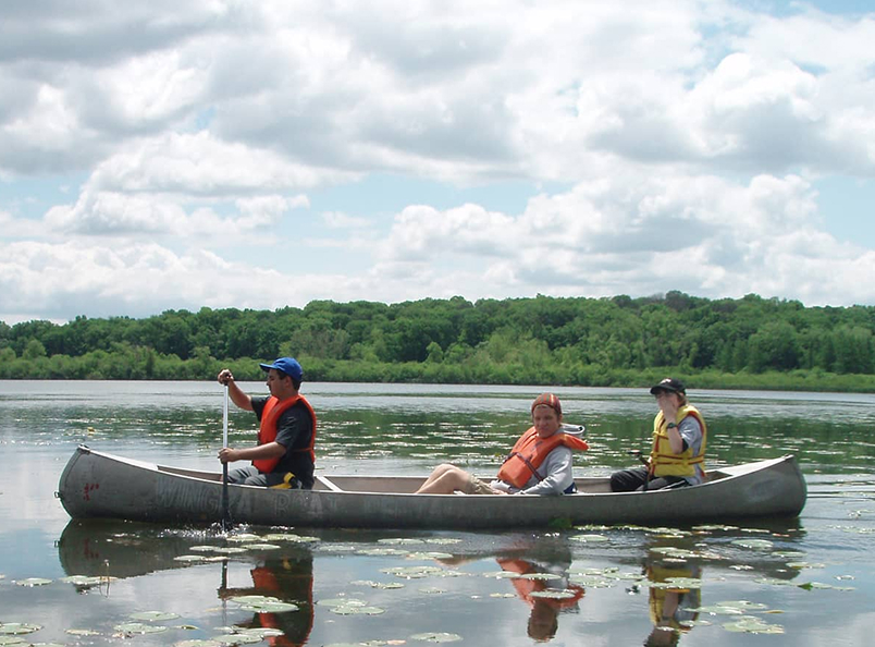 Three people in a canoe on the lake.