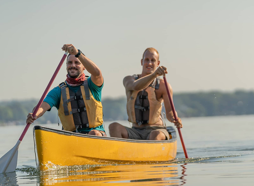 Two men rowing together in a kayak.