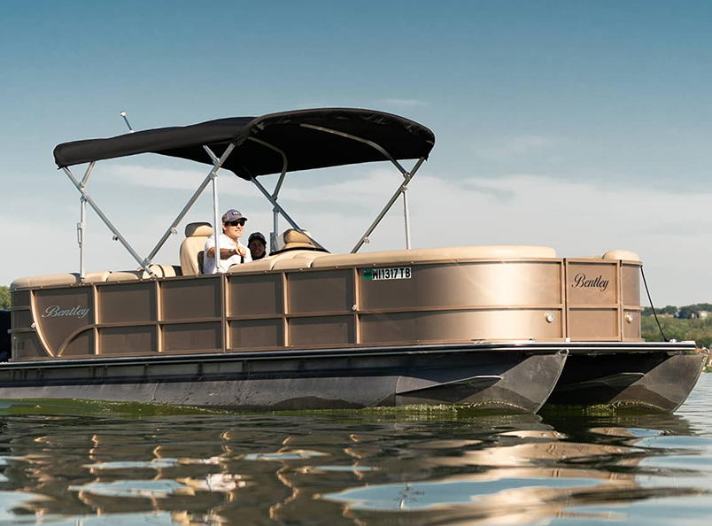 Two people in a pontoon boat on the lake.